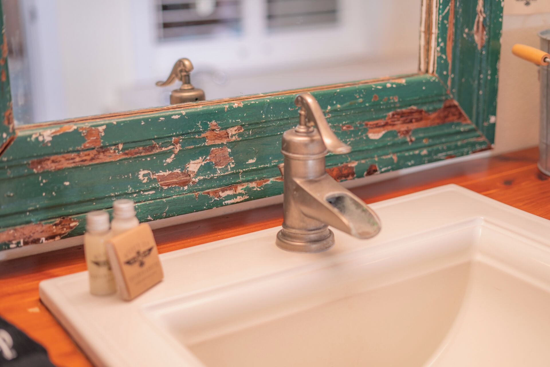 A bathroom sink with a vintage mirror and peeling paint.
