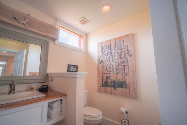 Experience the unique charm of this bathroom, featuring a wooden wall art piece and a mirror with a wooden frame.