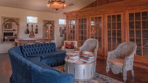 A spacious living room with a large blue sectional sofa, a round coffee table, and two ornate chairs. - The Rambler Room - Wander Inn (Round Top)