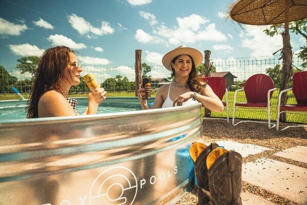 Two people in a hot tub with a logo 'POOLS' on the side.