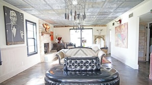 A spacious room with a large round table, a fireplace, and a chandelier. - Gypsy Farmhouse - Wander Inn (Round Top)