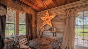 A rustic room with a wooden star decoration, a round table, and a view of the outdoors. - Thelma's Garage - Wander Inn (Round Top)