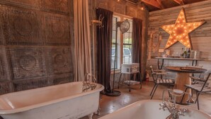 A rustic bathroom with two vintage clawfoot tubs, a wooden ceiling, and a star-shaped light fixture. - Thelma's Garage - Wander Inn (Round Top)
