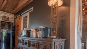 A rustic kitchen with a wooden ceiling, a built-in bar area, and a refrigerator. - Thelma's Garage - Wander Inn (Round Top)