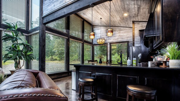 A modern kitchen with a large island, bar stools, and a leather couch. - 2Bdr with elevated design and bunkhouse! (Broken Bow)