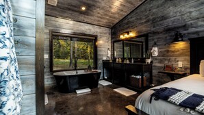 A modern bathroom with a freestanding bathtub, a large mirror, and a vanity. - 2Bdr with elevated design and bunkhouse! (Broken Bow)