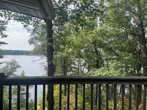 Une vue depuis une terrasse en bois donnant sur un lac, entourée d’une forêt dense.