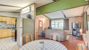 Een moderne keuken met houten kastjes, een koelkast en een eethoek met een ronde tafel en stoelen.