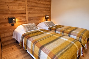 Une chambre avec deux lits, des murs en bois et des lampes fixées au mur.