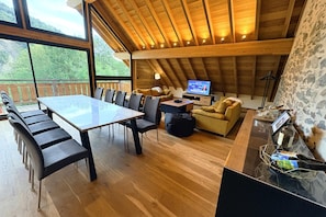 A spacious room with a large wooden table, comfortable seating, and a television. - Chalet Sert et Sagne 1 (Vaujany)