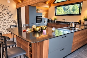A modern kitchen with a central island, built-in appliances, and a stone accent wall.