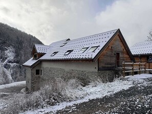 Eine Chalet mit geneigtem Dach, Steinwänden und einer Holzdiele.