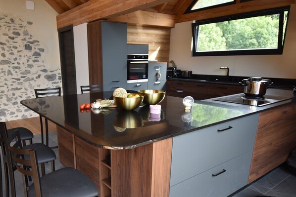 Een moderne keuken met een centraal eiland, houten keukenkastjes en een groot raam.