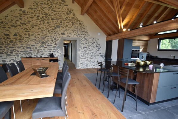 Une cuisine moderne avec un mur en pierre, une table à manger en bois et un coin bar.