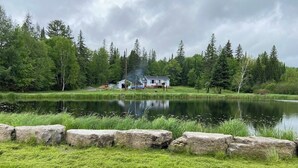 Eine Blockhütte am Seeufer mit einer Anlegestelle, umgeben von dichtem Wald und einem ruhigen See.