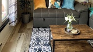 Ein Wohnzimmer mit einer Couch, einem Couchtisch, einer Zimmerpflanze und einem Bild an der Wand.