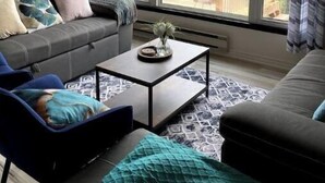 Ein Wohnzimmer mit Sofa, Sessel, Couchtisch und Deckenventilator.