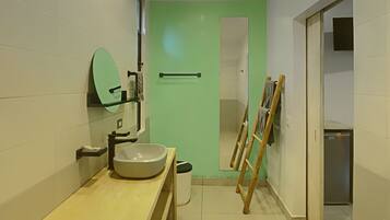 A modern bathroom with a large sink, mirror, and a green door leading to another room.