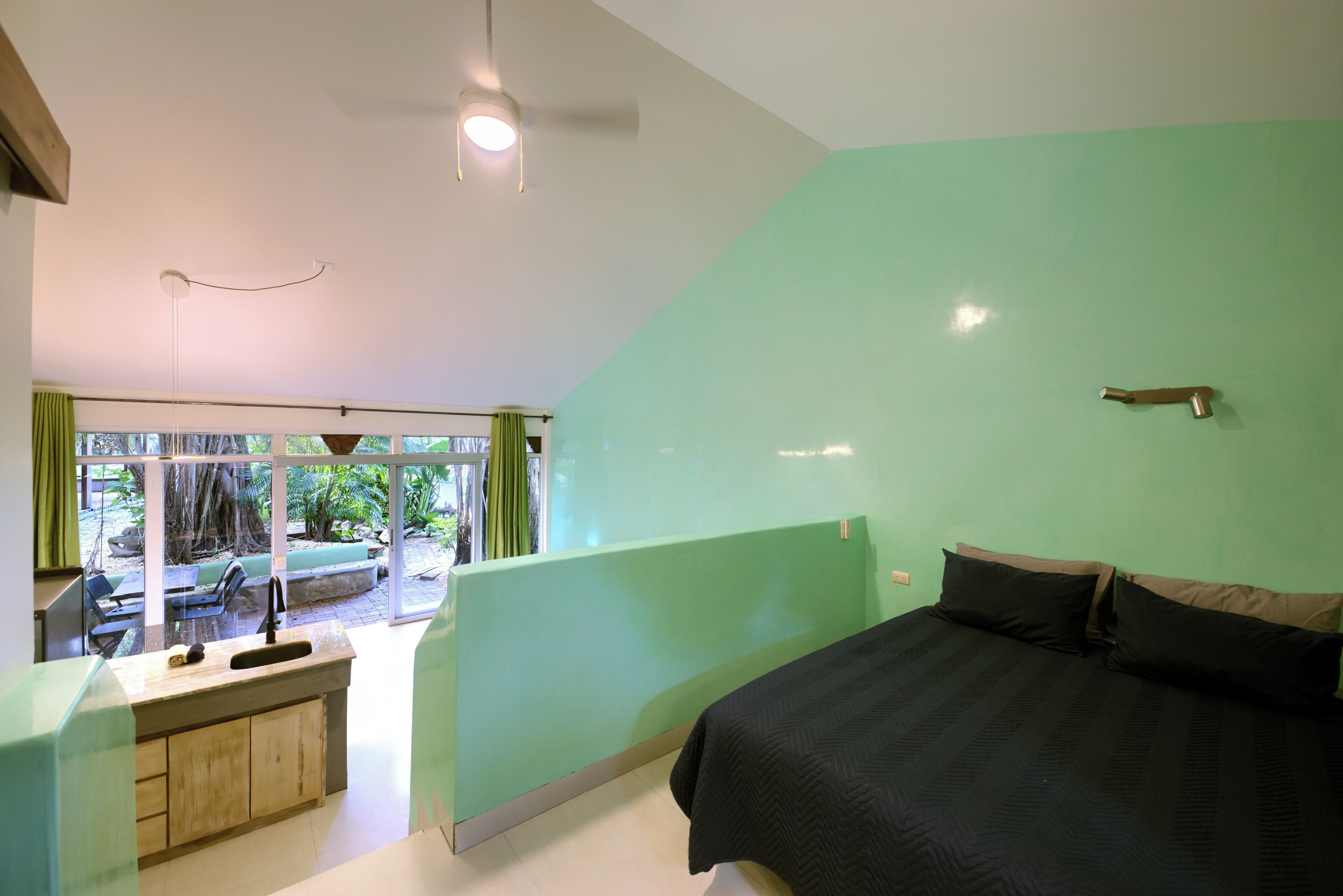 A bedroom with a bed, a window, a sink, and a view of the outdoors.