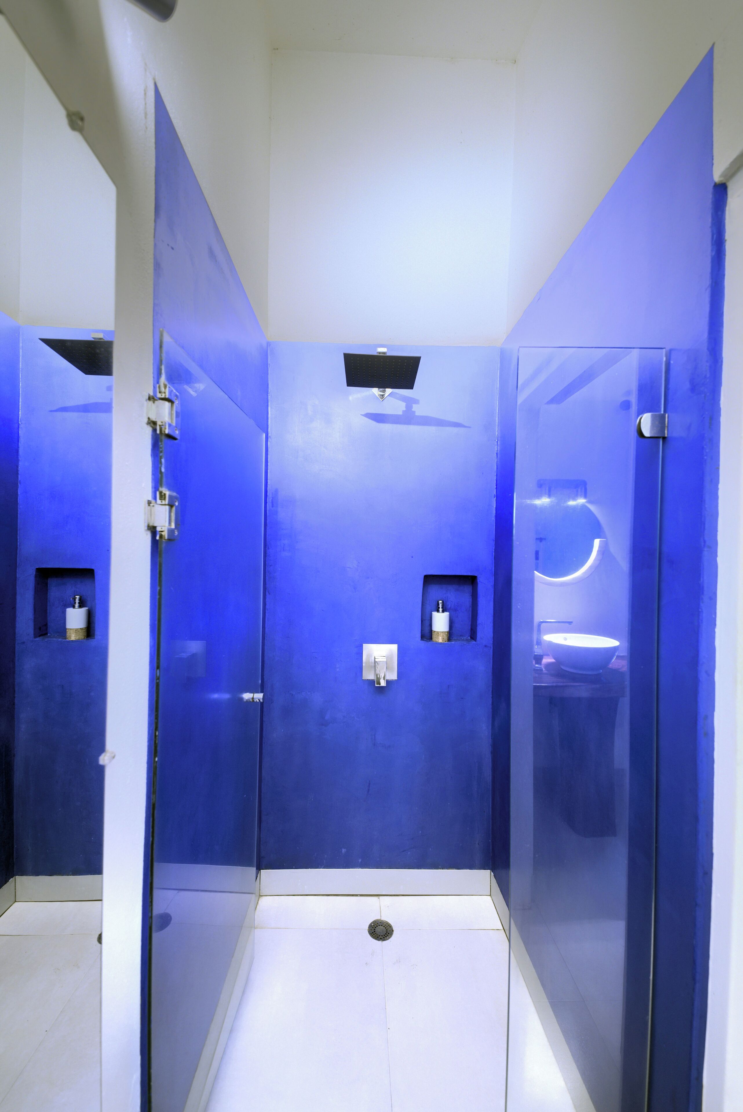 A modern bathroom with blue walls and a glass shower enclosure.