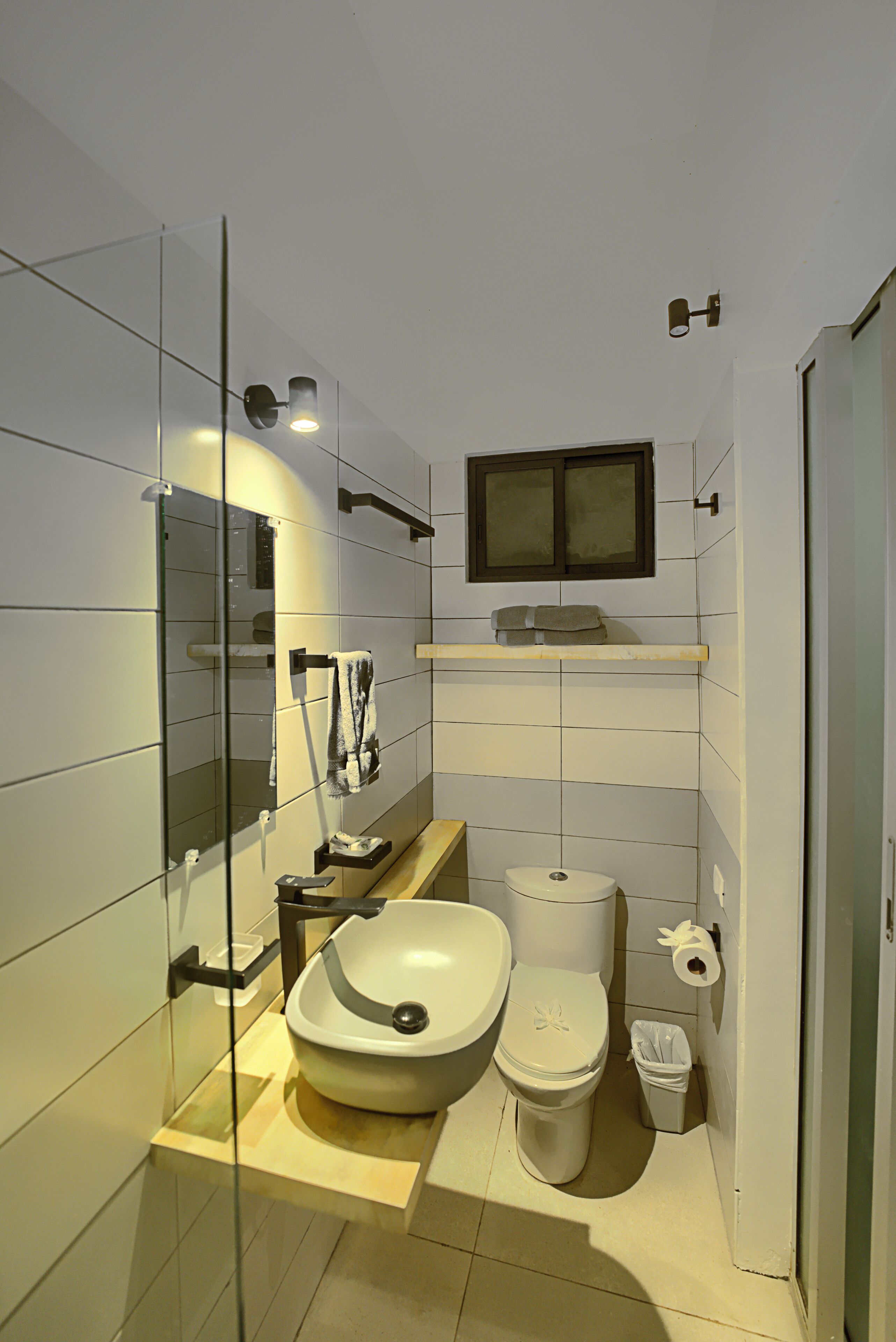 Ein modernes Badezimmer mit einer Duschkabine, einem weißen Waschbecken, einer Toilette und einem Spiegel über dem Waschbecken.