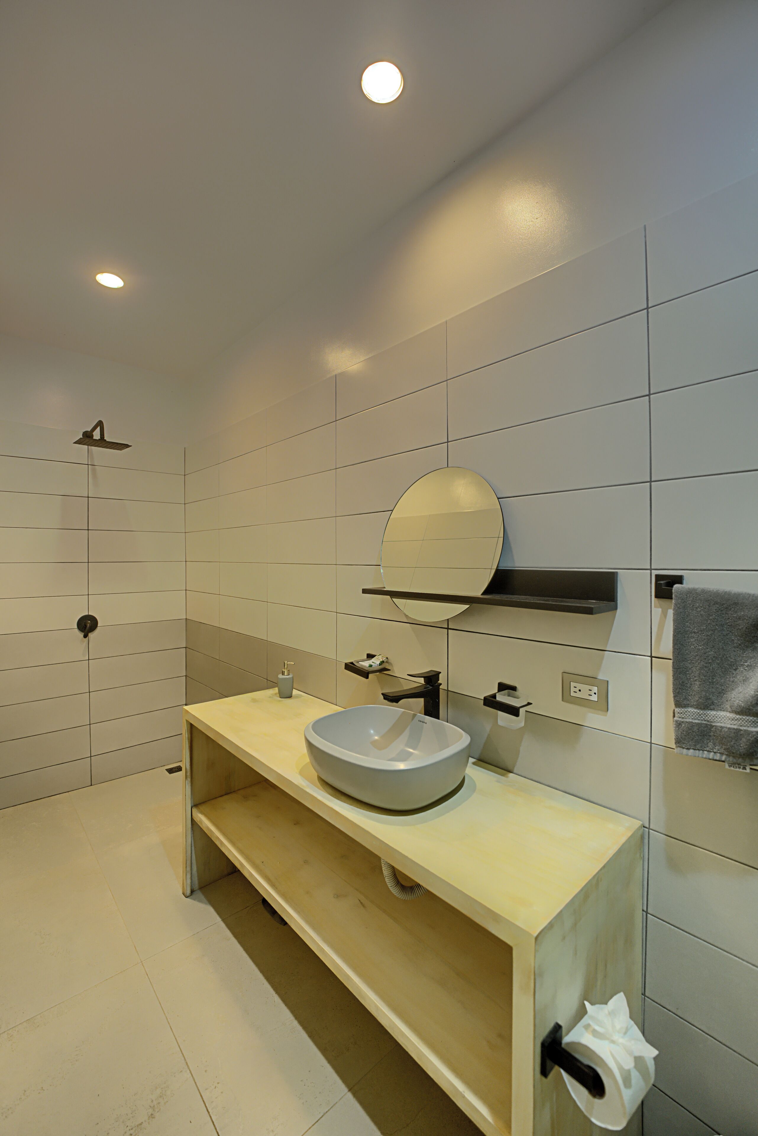 A modern bathroom with a wooden vanity, a large mirror, a built-in sink, and a shower.