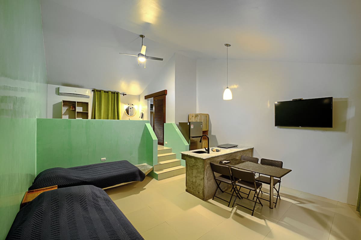Una habitación de hotel compacta con kitchenette, una zona de comedor y dos camas individuales.