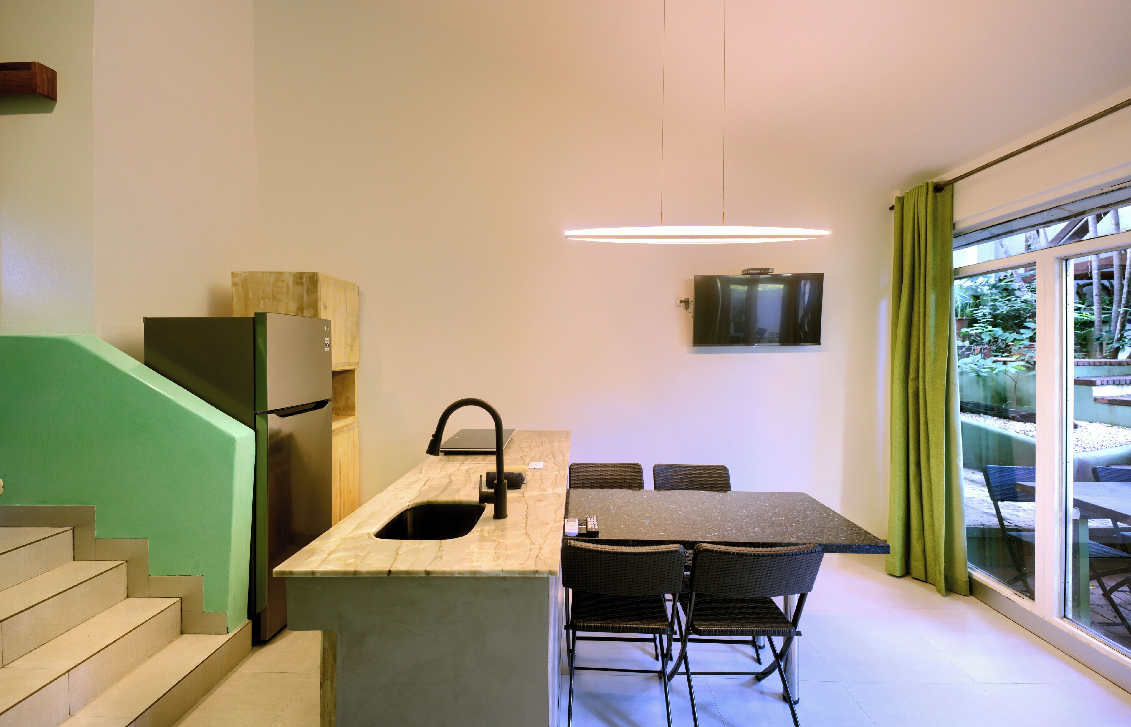 A modern kitchen with a built-in sink, a dining area with a table and chairs, and a large window with curtains.