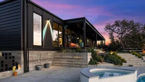 A modern house with a pool, large windows, and a well-lit outdoor area.