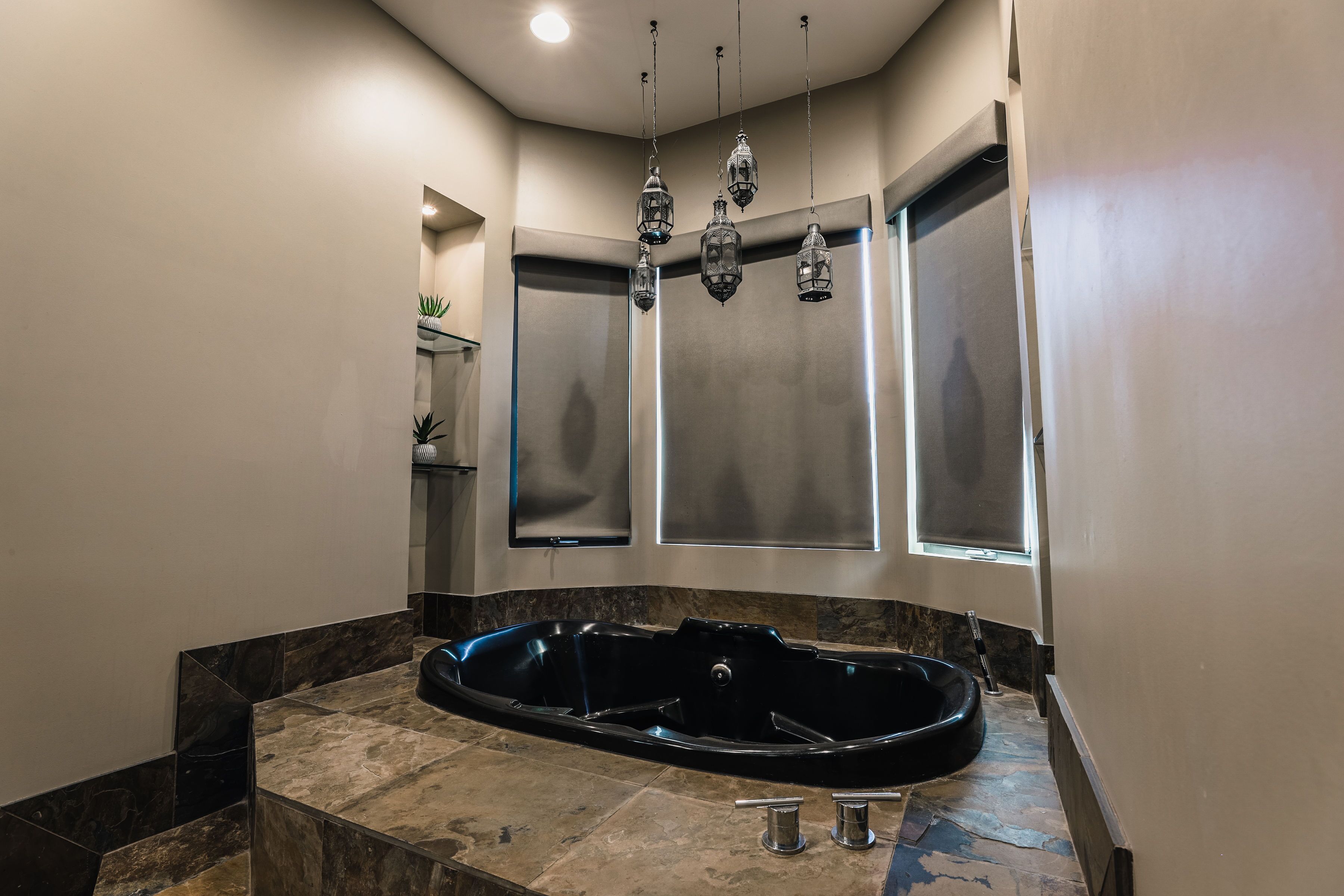A modern bathroom with a freestanding bathtub, a large mirror, and a potted plant.