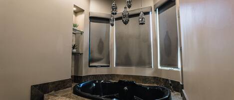 A modern bathroom with a freestanding bathtub, a large mirror, and a potted plant.