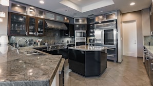 A modern kitchen with granite countertops, stainless steel appliances, and a central island. - The Galvan Estate (Palm Springs)
