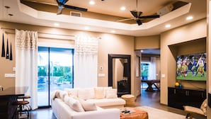 A modern living room with a sectional sofa, a pool table, and a flat-screen TV. - The Galvan Estate (Palm Springs)