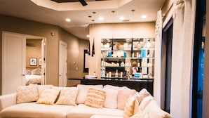 A modern living room with a sectional sofa, a coffee table, and a glass display cabinet in the background. - The Galvan Estate (Palm Springs)