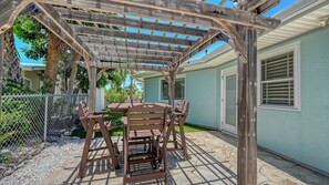 A covered patio with a wooden pergola, a table, and chairs. - BOOK THE MONTH FOR THE PRICE OF A WEEK!!! Spacious 2BR/2BA Home in Key Royale | Golf Community | 1-Month Minimum Stay (Holmes Beach)