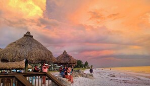 A beach with thatched-roof structures and a wooden walkway. - BOOK THE MONTH FOR THE PRICE OF A WEEK!!! Spacious 2BR/2BA Home in Key Royale | Golf Community | 1-Month Minimum Stay (Holmes Beach)