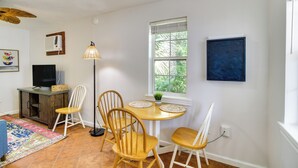 Een eethoek met een houten tafel, vier stoelen, een vloerlamp en een raam met jaloezieën.