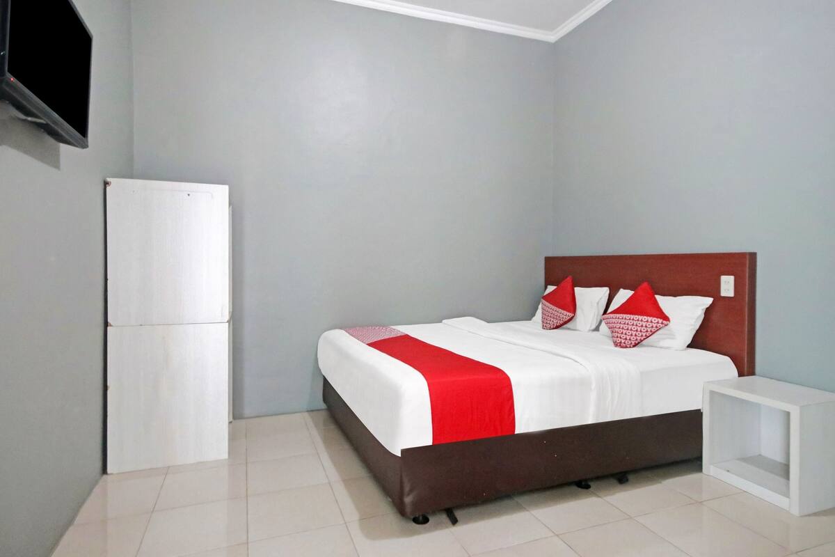 A bedroom with a bed, a white bedside table, and a white wardrobe.