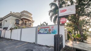 A residential building with a sign for SBH Residence by Suam, a gated entrance, and a poster advertising amenities like high-speed WiFi and smart TV. - OYO 90359 Sbh Residence (Medan)