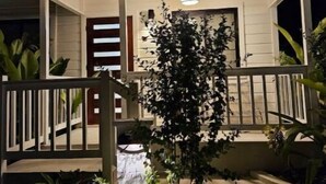 A two-story house with a porch, a small garden, and a visible door.