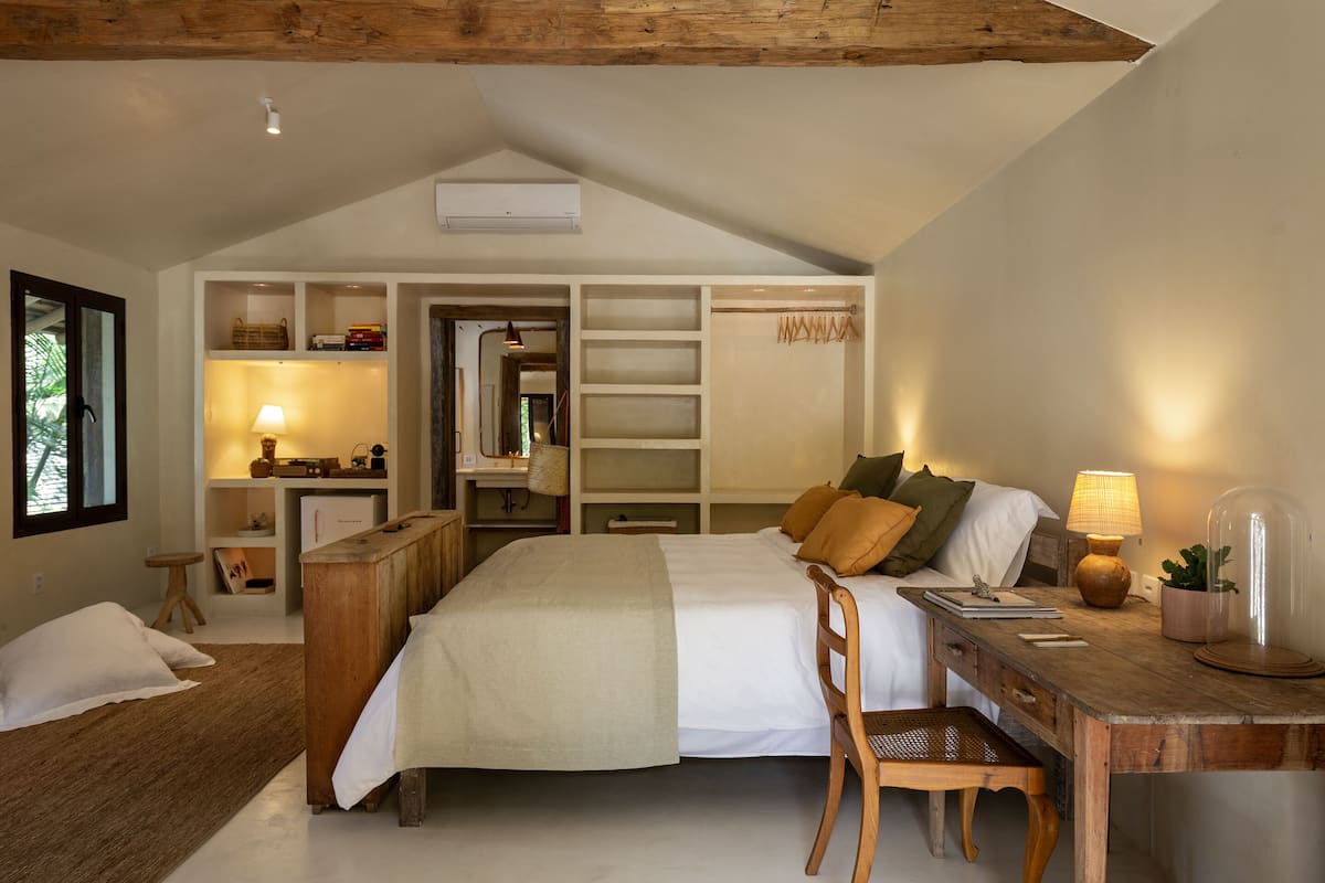 A bedroom with a bed, desk, chair, and shelves.