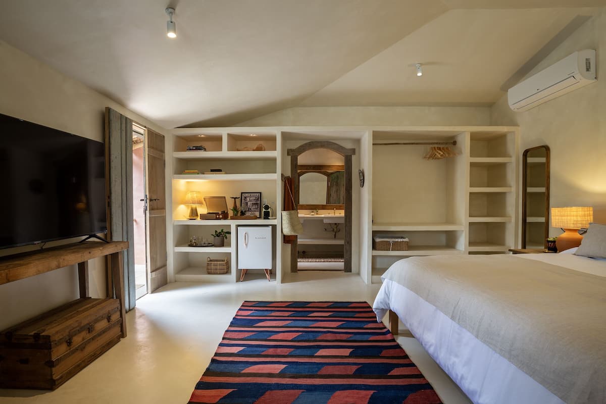 A bedroom with a bed, a TV, built-in shelving, and a wardrobe.