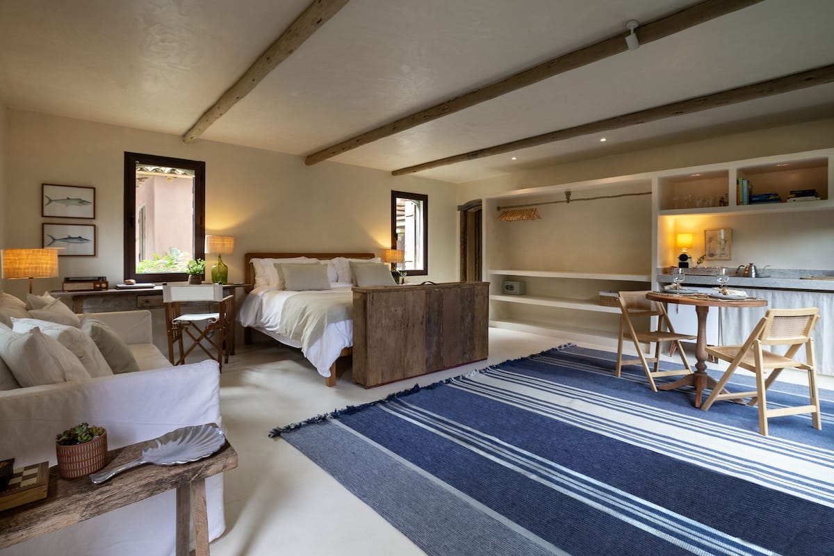 A spacious bedroom with a large bed, a desk, and a seating area with chairs.