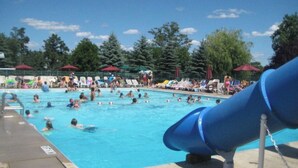 Ein Swimmingpool mit einer blauen Rutsche, umgeben von Liegestühlen und Sonnenschirmen.
