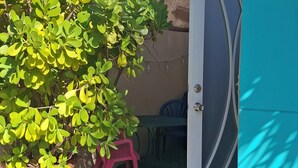 A potted plant in a terracotta pot, a pink plastic chair, and a blue door with a metal handle. - Stay as a tourist & feel as a local; Beach & Loiza st. strip, everything near! (San Juan)
