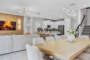 A modern kitchen with white cabinets, a central island, and stainless steel appliances. - New Home 8 Bedrooms and 5 Bathrooms At Storey Lake (Kissimmee)