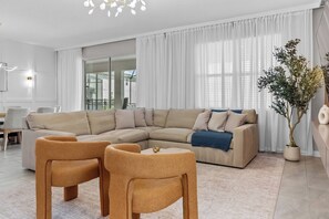 Ein modernes Wohnzimmer mit einer Eckcouch, zwei Sesseln, einem Couchtisch und einer Topfpflanze.