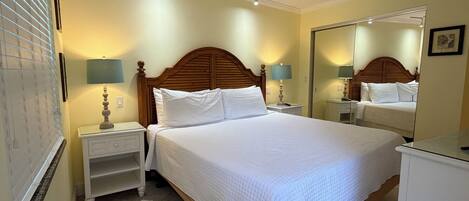 A hotel room with a large bed, bedside lamps, a ceiling fan, and a mirror.