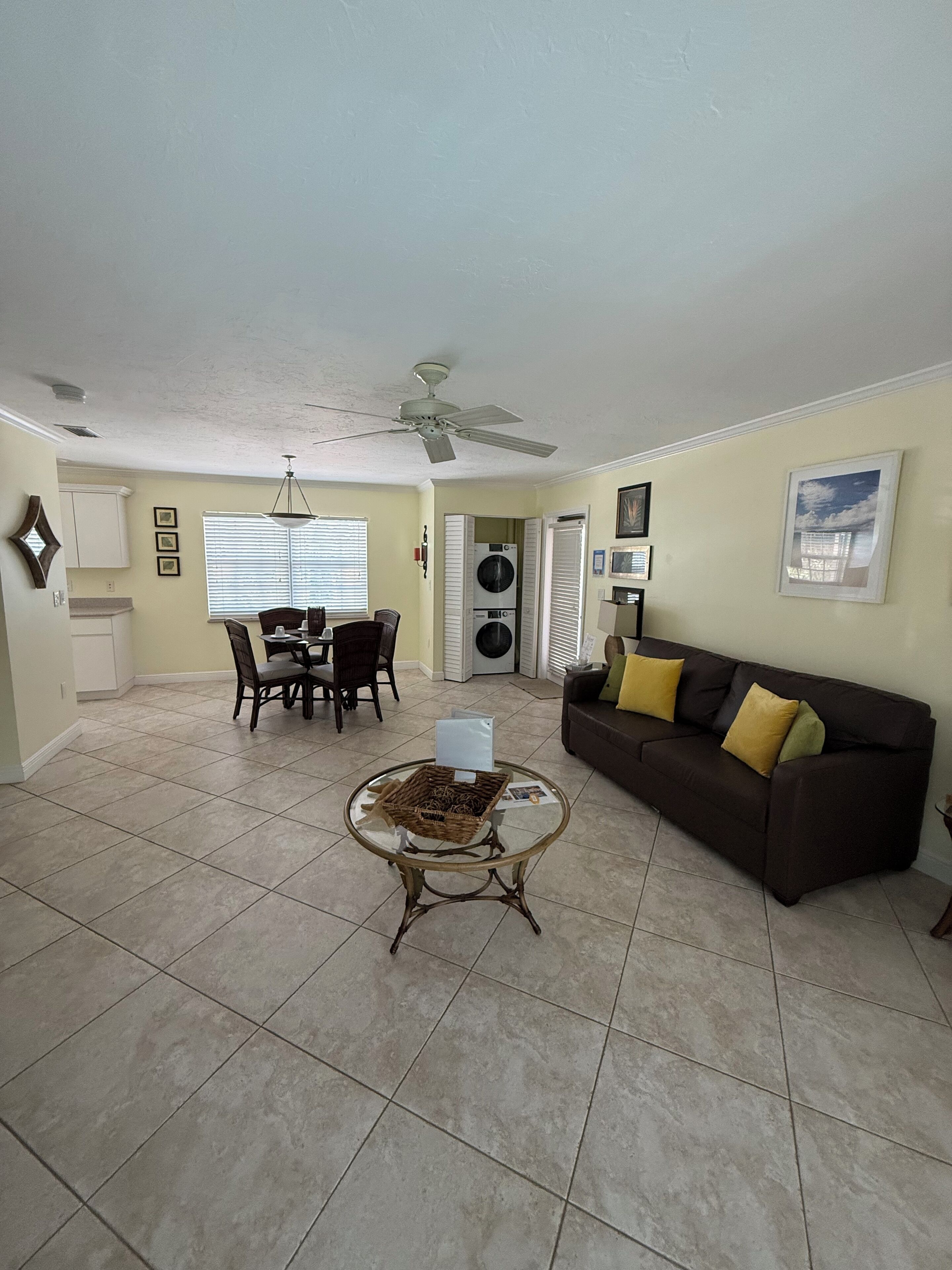 A living room with a dining area, a ceiling fan, a couch, and a table with a basket.