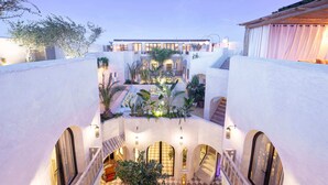 A courtyard with a checkered floor, arched doorways, and a central staircase leading to an upper level. - RIAD XO (Marrakech)